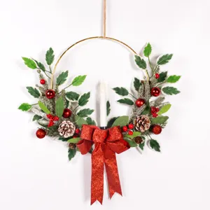 Détail de couronne de Noël suspendue avec feuilles givrées, baies rouges et nœud scintillant.