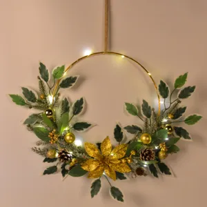Close-up detail of Christmas wreath with golden leaves, pinecones, and LED string lights.