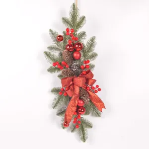 Decorazione natalizia da appendere con pigne, bacche rosse e un fiocco rosso festivo.