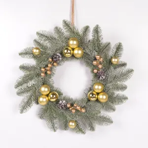 Detailed view of frosted pine needle Christmas wreath with gold ornaments, pinecones and berries.