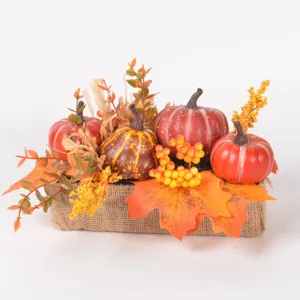 Detailed view of autumn artificial pumpkins, maple leaves, and colorful berries in a burlap base.
