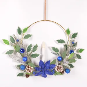 Christmas candle wreath wall hanging with blue poinsettia pine needles pinecones and candles.