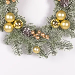 Detailed close-up of Christmas wreath with frosted pine needles and gold ornaments.