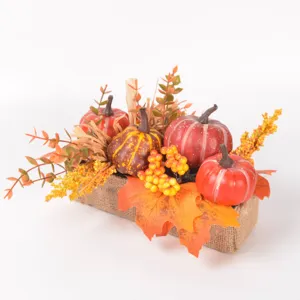 Detailed close-up of autumn artificial pumpkins, maple leaves, and berries in burlap base.