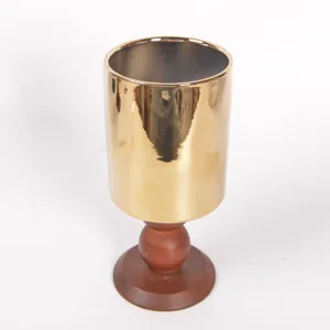 Coppa in metallo dorato retrò con base in legno, porta candela di lusso e vaso di fiori.