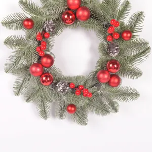 Detailed view of Christmas wreath featuring red ornaments, pine cones, and frosted pine needles.