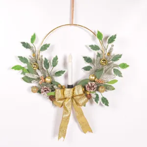 Détail de couronne de bougie de Noël avec anneau doré, plantes artificielles et nœud festif.