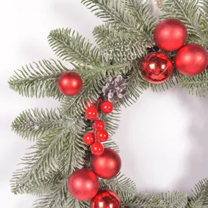 Christmas wreath decoration with frosted pine needles red balls and pinecones for holiday decor