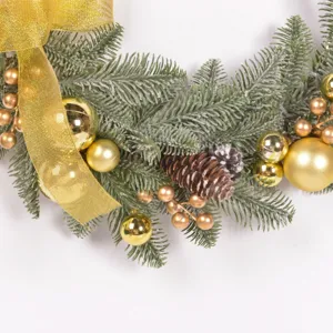 Detail of Christmas wreath with frosted pine needles, gold ribbon, and shiny ornaments.