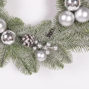 Christmas wreath detail closeup featuring frosted pine needles and silver ball ornaments.