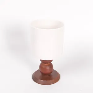 Primo piano dettagliato che mostra la tazza in ceramica liscia e la base in legno.