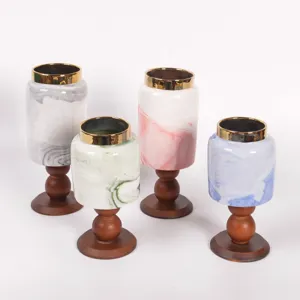 Portacandele vintage in ceramica marmo con piedistallo in legno e bordo dorato.