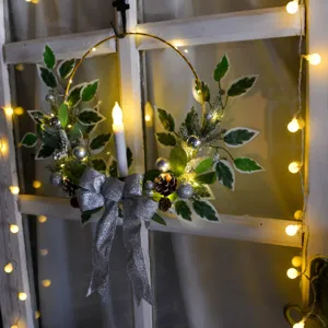 Détail de couronne de Noël avec bougeoir, feuilles artificielles et nœud argenté.