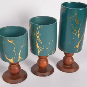 Primo piano dettaglio di portacandela in ceramica verde retro con base in legno e oro.