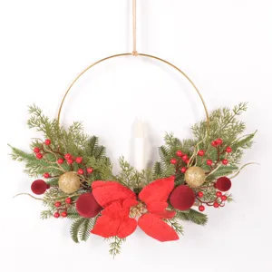 Detailaufnahme des Weihnachtskranzes mit rotem Weihnachtsstern Samtkugeln Tannenzweigen und Kerze.