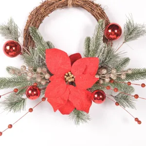 Christmas rattan wreath detail featuring red poinsettia, frosted pine and festive berries.