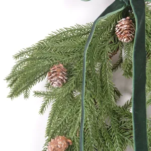 Christmas artificial pine garland wreath detail with pine cones and green velvet ribbon.