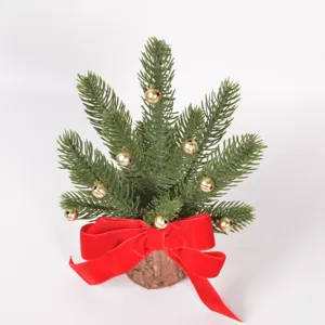 Mini Christmas tree detail shot featuring wooden base, green pine branches, and golden bells.