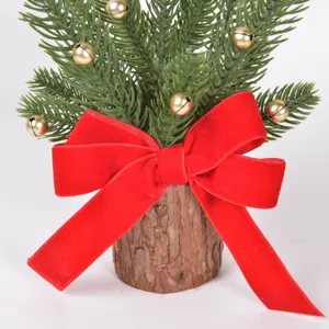 Mini Christmas tree detail with green pine branches, gold bells, and large red velvet bow.