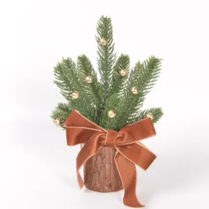 Mini Christmas tree detail with wooden log base, gold bells and velvet bow for holiday decor.