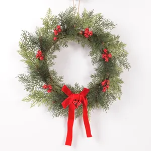 Detailed view of Christmas wreath featuring faux pine branches, red berries, and velvet bow.