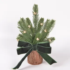 Mini Christmas tree detail view, featuring wood base, pine branches, and a green velvet bow.