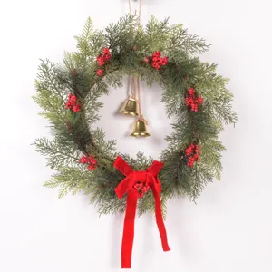 Detailed close-up of Christmas wreath with pine branches, red berries, bells and velvet bow.