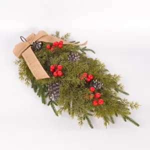 Detailansicht künstlicher Weihnachts-Kieferngirlande mit roten Beeren und Zapfen für Feiertage.