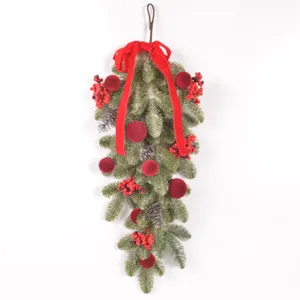 Artificial Christmas teardrop swag with pine branches and red velvet balls for door decor.