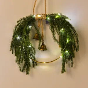 Christmas wreath detail showing Norfolk pine needles, warm fairy lights, and cute hanging bells.