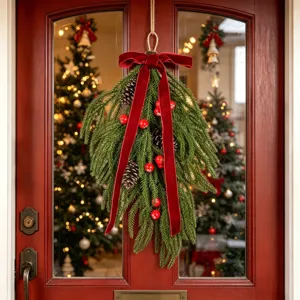 Gros plan sur la guirlande de Noël en forme de larme avec nœud en velours sur une porte.