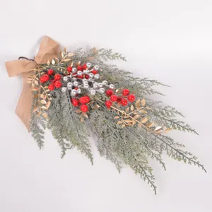 Detailed view of Christmas hanging teardrop swag with pine branches, berries and bow.