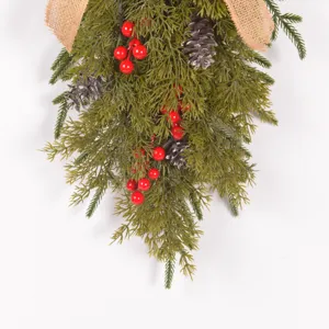 Weihnachtsgirlande mit künstlichen Zweigen, Zapfen, roten Beeren und Juteschleife.