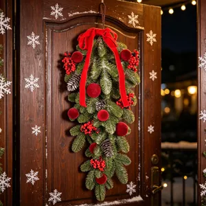 Christmas teardrop swag hanging on dark wood door close up view holiday decor detail