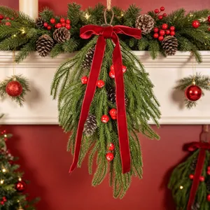 Détail de guirlande de Noël en larme, avec branches persistantes, pommes de pin et nœud rouge.