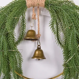 Detailed view of Christmas Norfolk pine wreath with rustic bells and fairy lights for decor.