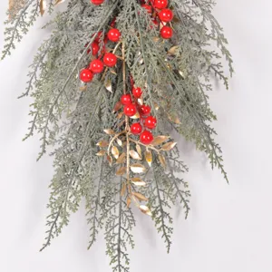 Artificial Christmas hanging pine branch with red berries and gold leaves detail shot.