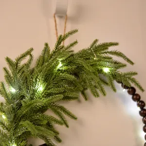 Detailed closeup of Norfolk pine and wooden bead Christmas wreath wall hanging decor