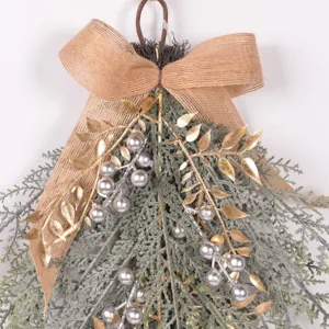 Detail view of artificial Christmas teardrop swag with flocked pine, gold leaves, and berries.