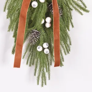 Guirlande de Noël en forme de larme suspendue avec branches de pin, pommes de pin et ruban.