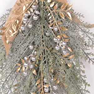 Artificial Christmas teardrop wreath detail with pine branches and silver berries decor.