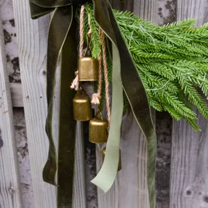 Close-up detail of Christmas rustic hanging bell decoration with velvet ribbon and pine.