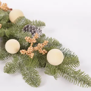 Detailed shot of frosted pine needle Christmas teardrop swag with pinecones and golden snowflakes.