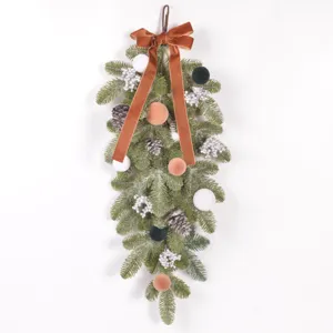 Christmas teardrop swag detail, artificial pine branch with velvet balls and ribbon for decor.