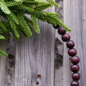 Detailed shot of Christmas Norfolk pine wood bead wreath wall hanging for holiday decor.