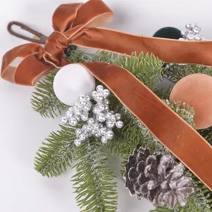 Detailed shot of Christmas teardrop swag featuring velvet bow, frosted pinecones and silver berries.