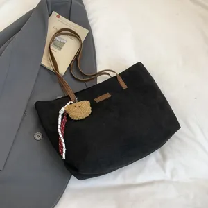Detailed view of the large black suede tote bag with brown handles and a cute bear charm.