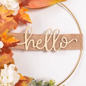 Close-up detail of autumn metal wreath with artificial maple leaves, white flowers and hello sign.
