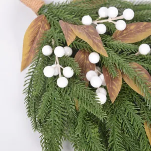 Close-up of artificial Norfolk pine needles with white berries and brown leaves for holiday decor