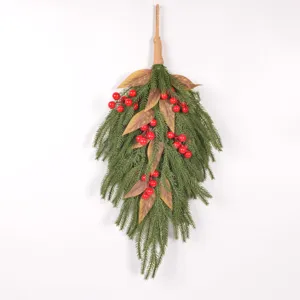 Close-up detail of artificial Norfolk pine branch with red berries for Christmas wall decor.